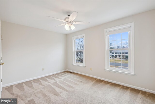 empty room featuring light carpet, baseboards, visible vents, and a ceiling fan