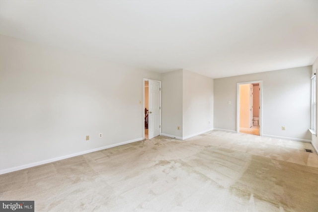 spare room featuring visible vents, baseboards, and light colored carpet