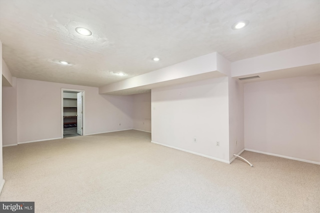 finished below grade area featuring recessed lighting, visible vents, baseboards, and light colored carpet