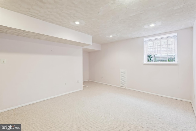 below grade area with a textured ceiling, recessed lighting, carpet floors, visible vents, and baseboards