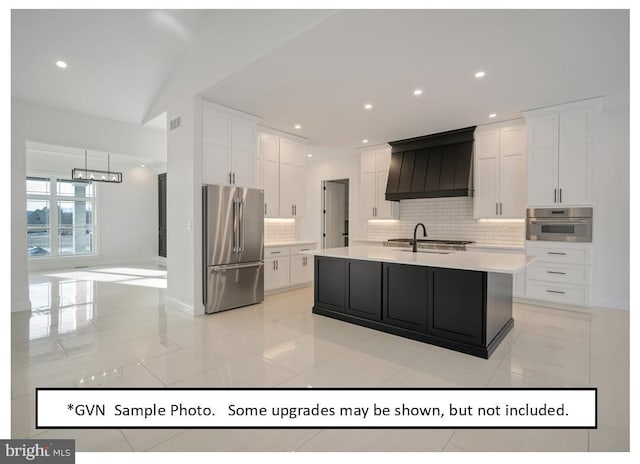 kitchen featuring a kitchen island with sink, premium range hood, sink, appliances with stainless steel finishes, and white cabinets