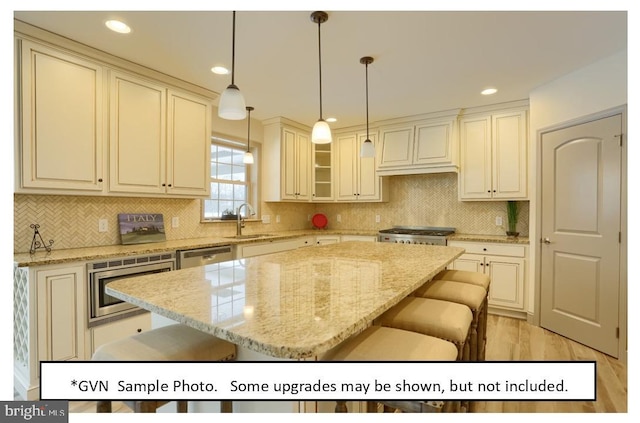 kitchen featuring pendant lighting, light stone countertops, a kitchen island, and a breakfast bar area