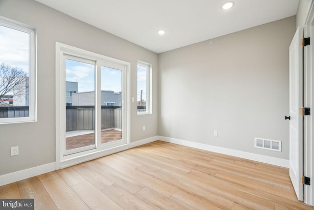 empty room with light wood-style flooring, recessed lighting, visible vents, and baseboards