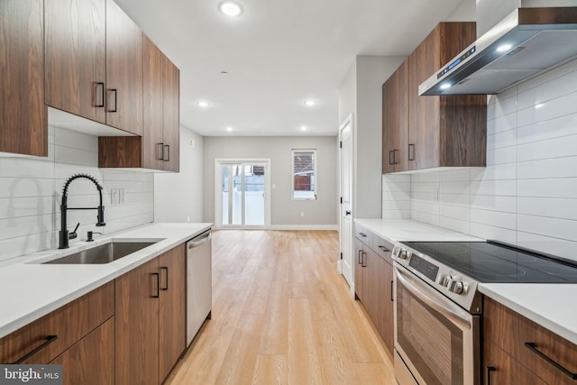 kitchen featuring a sink, light countertops, appliances with stainless steel finishes, and exhaust hood