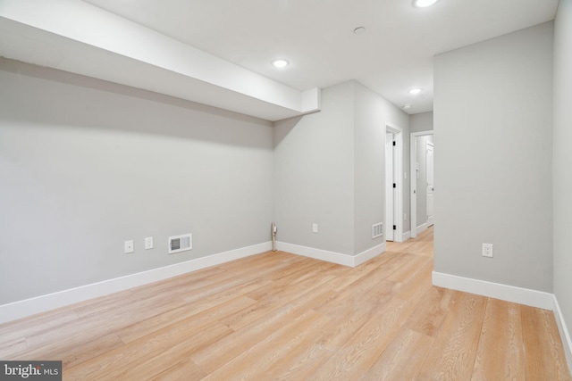 finished below grade area with light wood finished floors, recessed lighting, visible vents, and baseboards