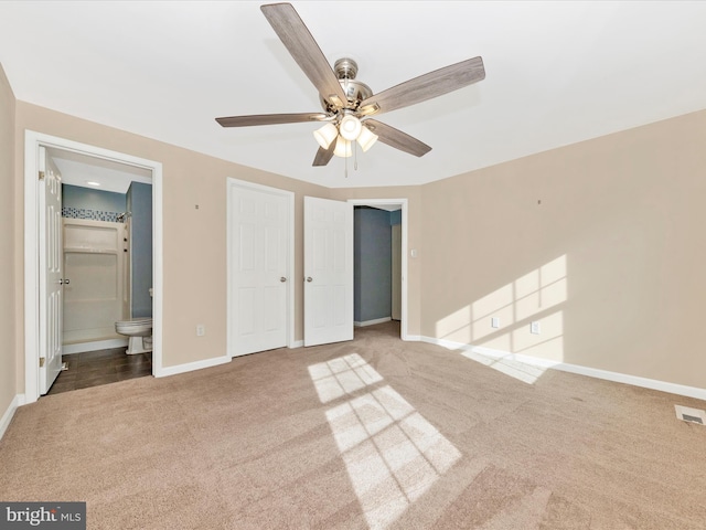 unfurnished bedroom with ceiling fan, carpet flooring, and ensuite bath