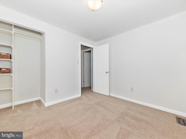 unfurnished bedroom with a closet and light colored carpet