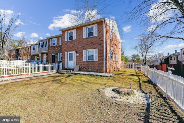 view of front of home with a residential view, brick siding, a fenced backyard, and a front lawn