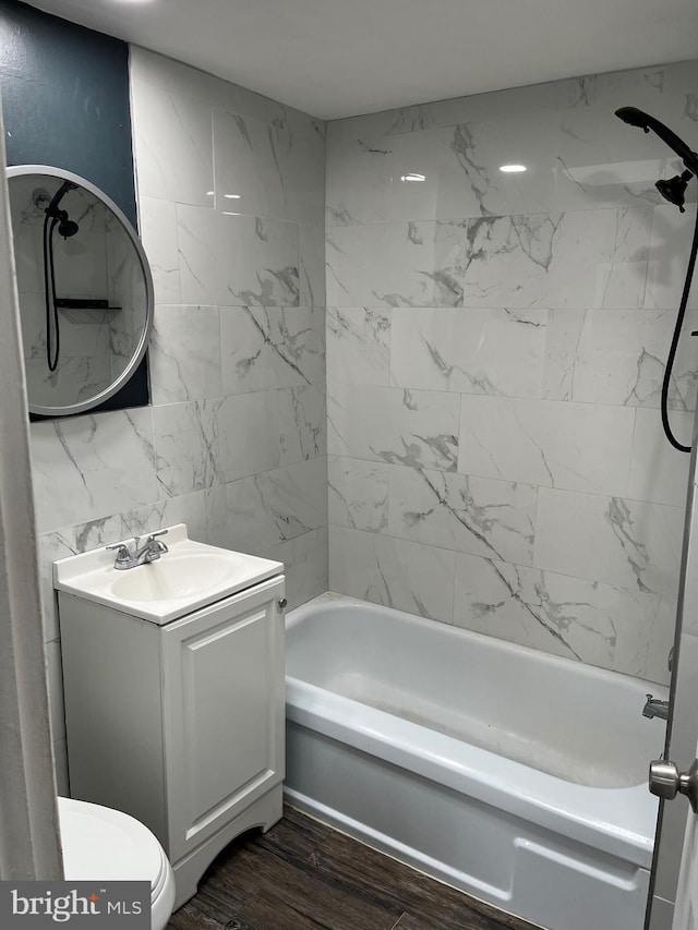 full bathroom featuring toilet, tiled shower / bath combo, vanity, and wood-type flooring