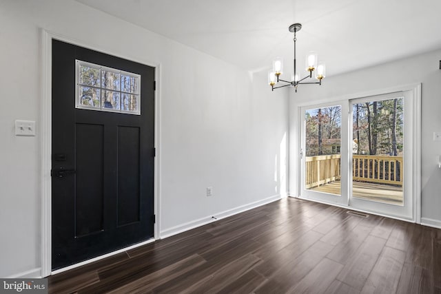 foyer entrance featuring dark hardwood / wood-style floors and a notable chandelier