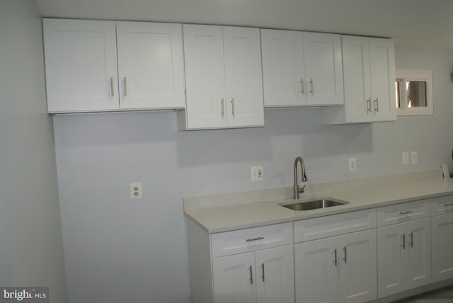 kitchen with light countertops, a sink, and white cabinets