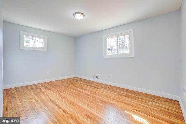 unfurnished room featuring light wood-style flooring, visible vents, and baseboards