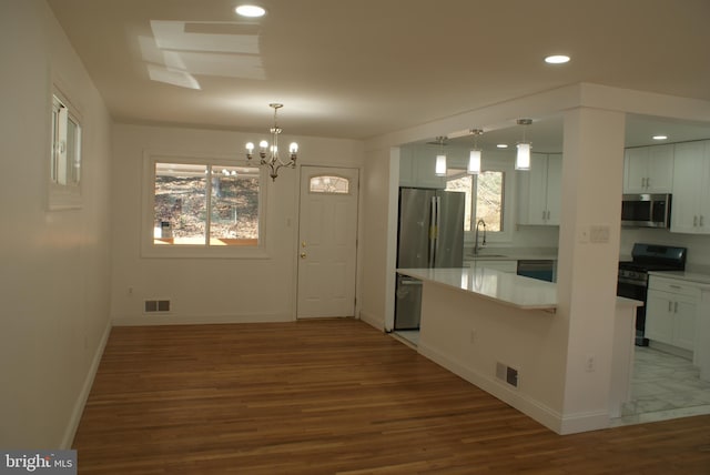 kitchen with appliances with stainless steel finishes, wood finished floors, visible vents, and white cabinets