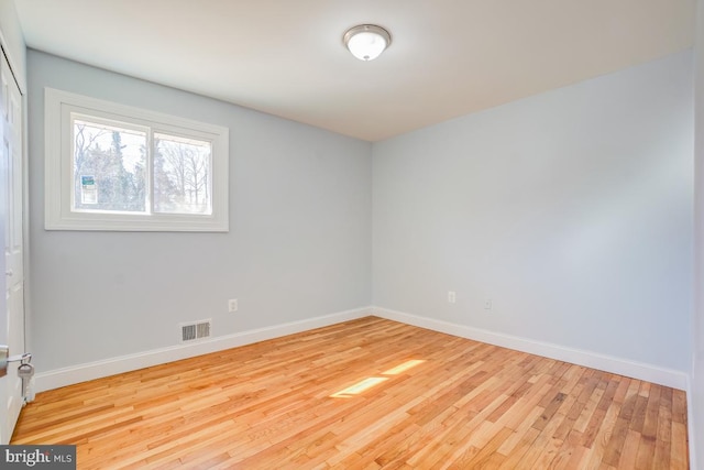 spare room featuring light wood-type flooring, baseboards, and visible vents