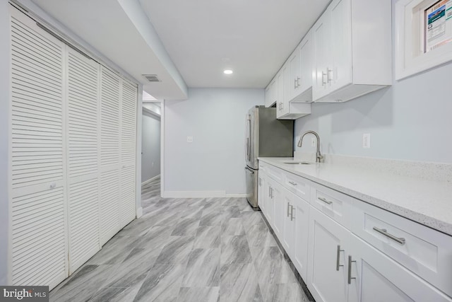 kitchen featuring visible vents, a sink, baseboards, and white cabinetry