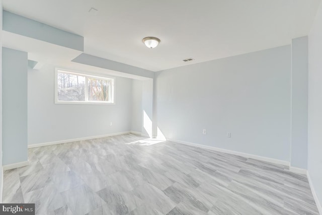 spare room with light wood-type flooring, visible vents, and baseboards