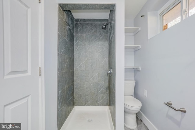 bathroom featuring a stall shower, toilet, and baseboards