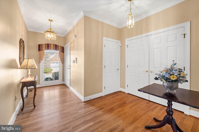 foyer featuring crown molding, an inviting chandelier, and wood-type flooring