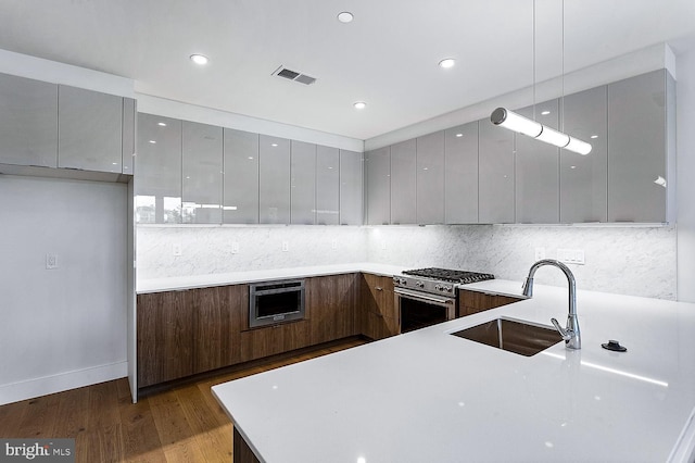 kitchen featuring hardwood / wood-style floors, sink, high end range, and decorative backsplash