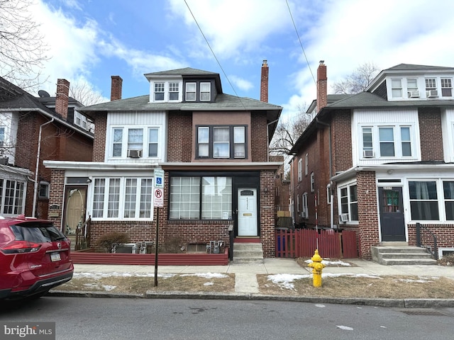 american foursquare style home with entry steps, brick siding, fence, and a chimney