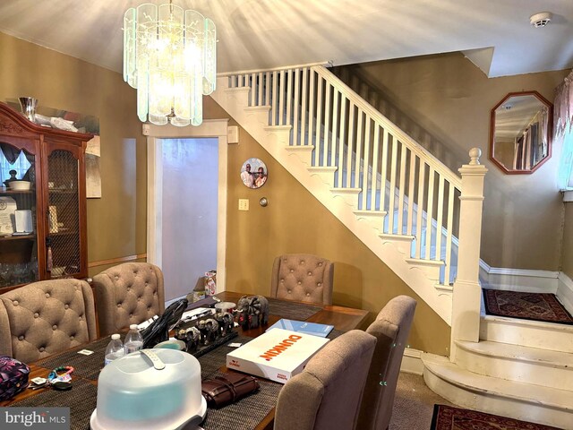 carpeted dining space featuring a chandelier, stairway, and baseboards