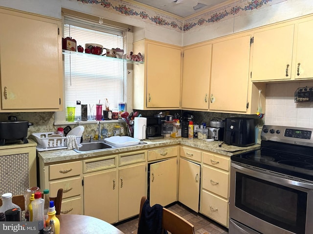 kitchen with a sink, decorative backsplash, light countertops, and electric stove