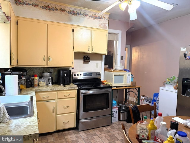 kitchen with tasteful backsplash, white microwave, stainless steel electric range, light countertops, and a sink