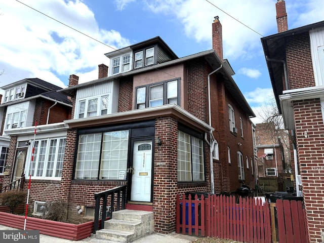 american foursquare style home featuring entry steps, brick siding, and fence private yard