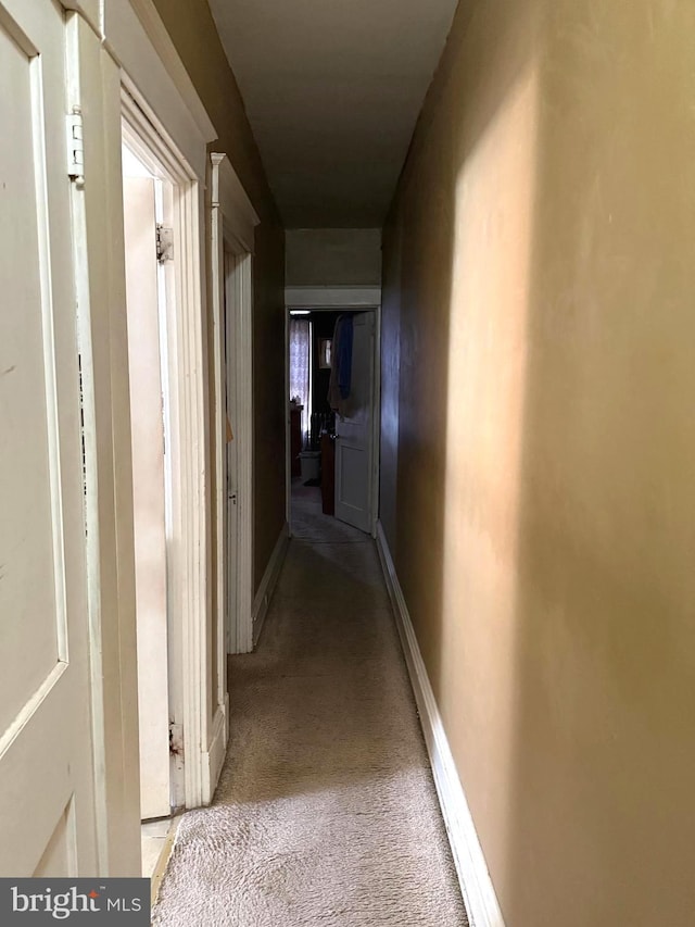 hall featuring light carpet and baseboards