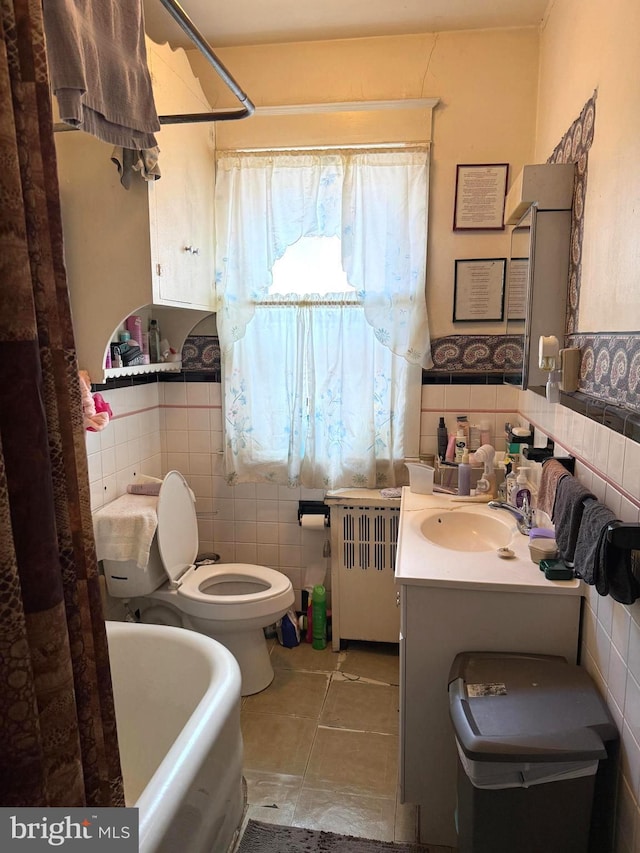 bathroom with toilet, radiator heating unit, tile walls, and vanity