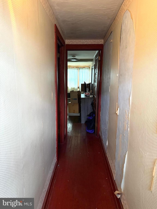 hall featuring dark wood-type flooring and baseboards