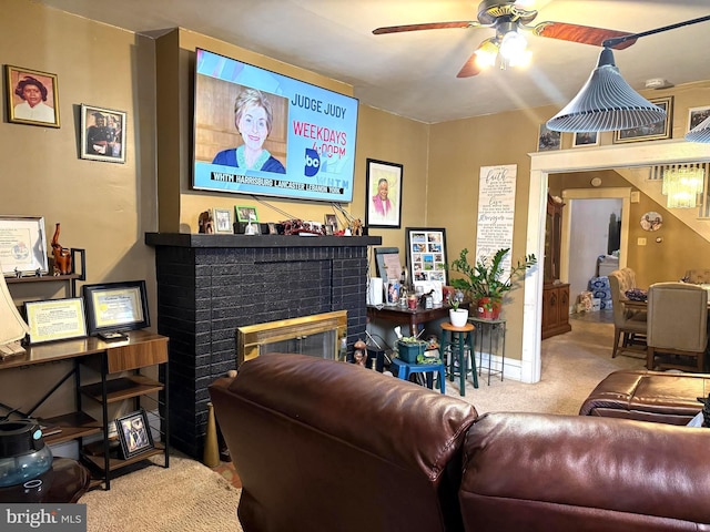 living room featuring ceiling fan, a fireplace, baseboards, and light colored carpet