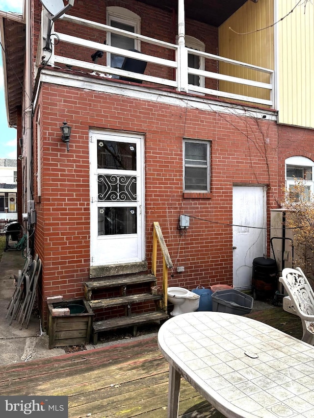 rear view of house featuring entry steps, brick siding, and a balcony