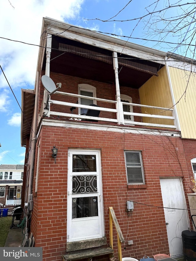 doorway to property with a balcony and brick siding