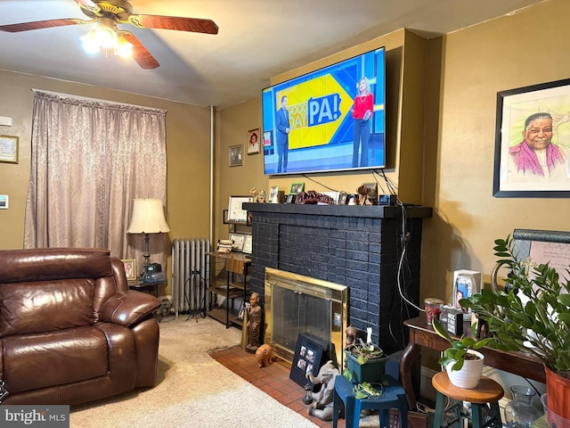 living area featuring light carpet, ceiling fan, radiator heating unit, and a brick fireplace