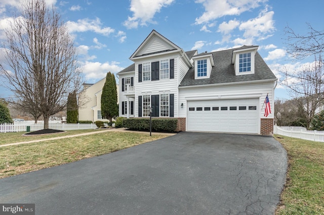 view of front facade with brick siding, a front lawn, an attached garage, and fence