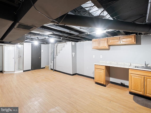 basement with sink, built in desk, and light hardwood / wood-style floors