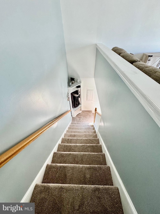 stairway featuring baseboards and carpet