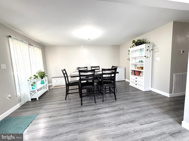 dining room featuring visible vents, baseboards, and wood finished floors