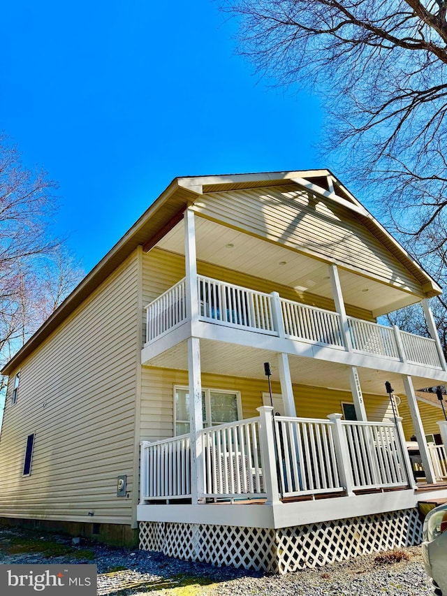 view of side of home with a balcony, covered porch, and crawl space