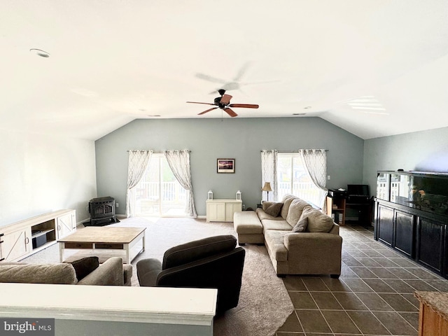 living area featuring vaulted ceiling, a wood stove, a ceiling fan, and dark tile patterned flooring