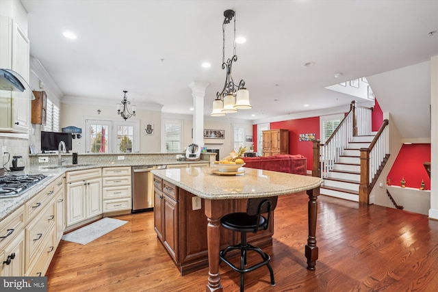 kitchen with light stone countertops, open floor plan, appliances with stainless steel finishes, a kitchen breakfast bar, and light wood-style floors