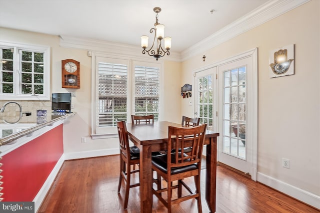 dining area featuring a notable chandelier, wood finished floors, baseboards, and ornamental molding