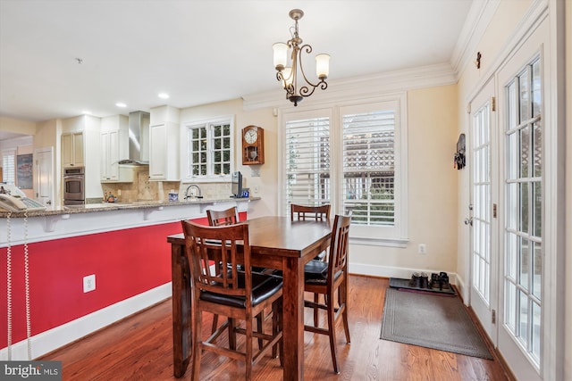 dining area with wood finished floors, baseboards, recessed lighting, ornamental molding, and a chandelier