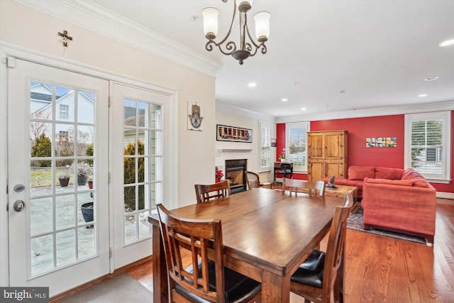 dining room featuring wood finished floors, crown molding, plenty of natural light, and a fireplace