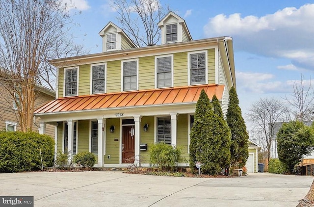 view of front of home with a garage, a standing seam roof, a porch, concrete driveway, and metal roof