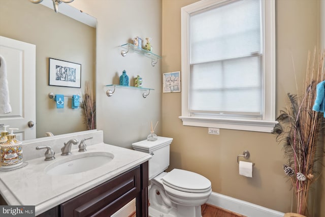 bathroom with baseboards, toilet, and vanity