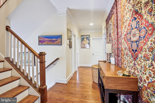 hallway with stairway, crown molding, baseboards, and wood finished floors