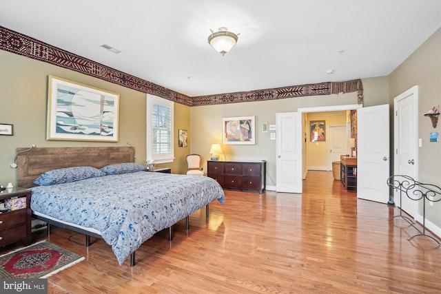 bedroom featuring baseboards, visible vents, and light wood finished floors