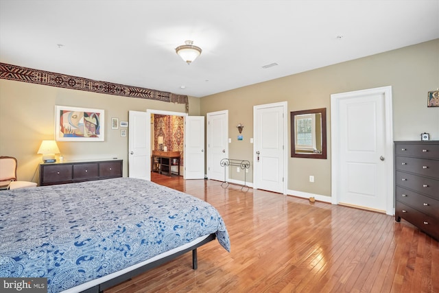 bedroom with visible vents, baseboards, two closets, and light wood-style flooring